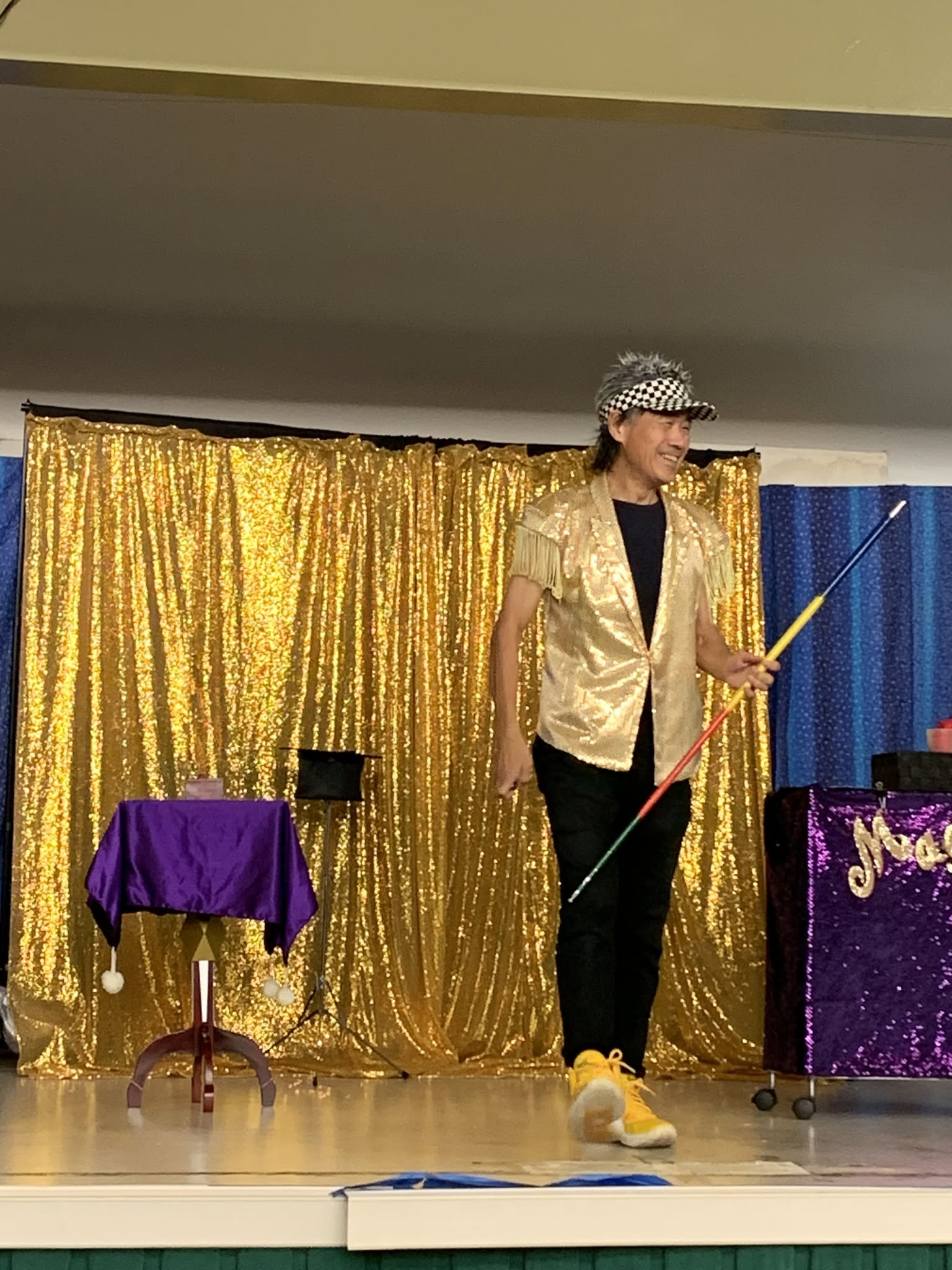 Magic performer on stage with gold sequin backdrop