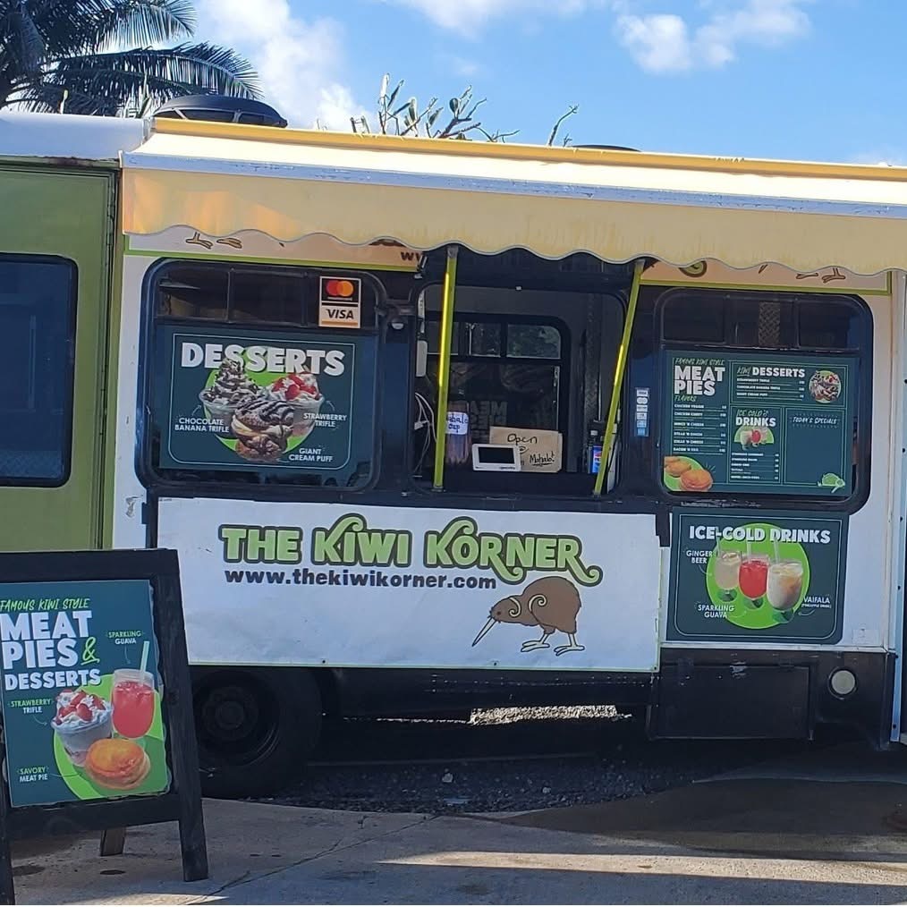 The Kiwi Korner green and white food truck with menu boards, parked under palm trees in Laie, Hawaii